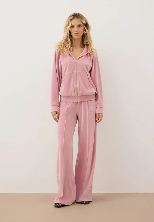 Modelka ubrana w różowy, welurowy dres - bluza IANELLA oraz spodnie VELORINA