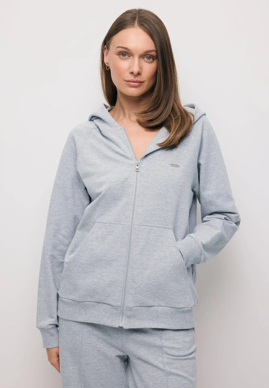 Zbliżenie na modelkę z ręką w kieszeni rozpinanej, szarej bluzy z kapturem IANELLA.