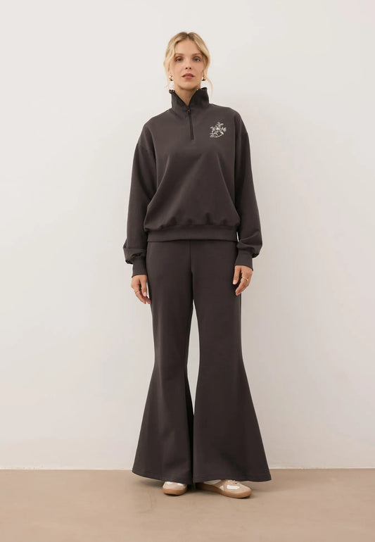 Modelka ubrana w czekoladowy dres z bluzą half zip TANSY i spodniami z szerokimi nogawkami ZEIA.