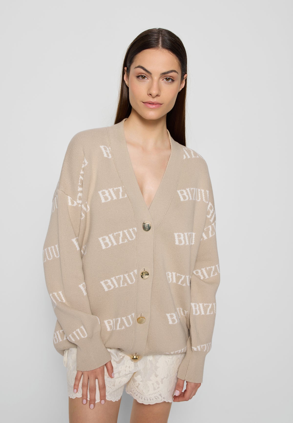 Modelka na białym tle ubrana w beżowy sweter z logo Bizuu Kyle oraz koronkowe spodenki Nilda.