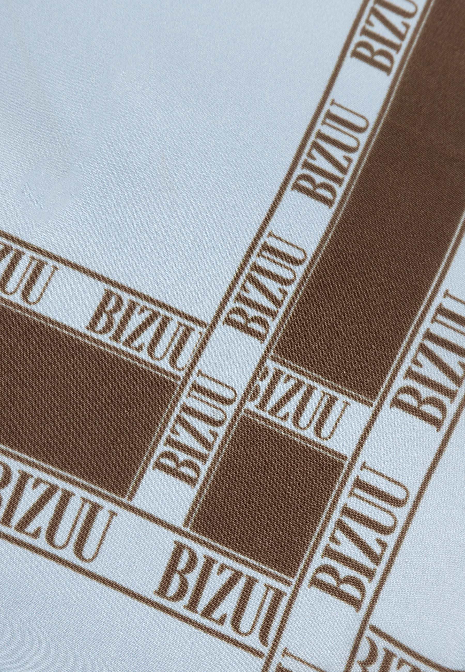 Zbliżenie na brązowe logo na niebieskiej, jedwabnej apaszce ARIA.