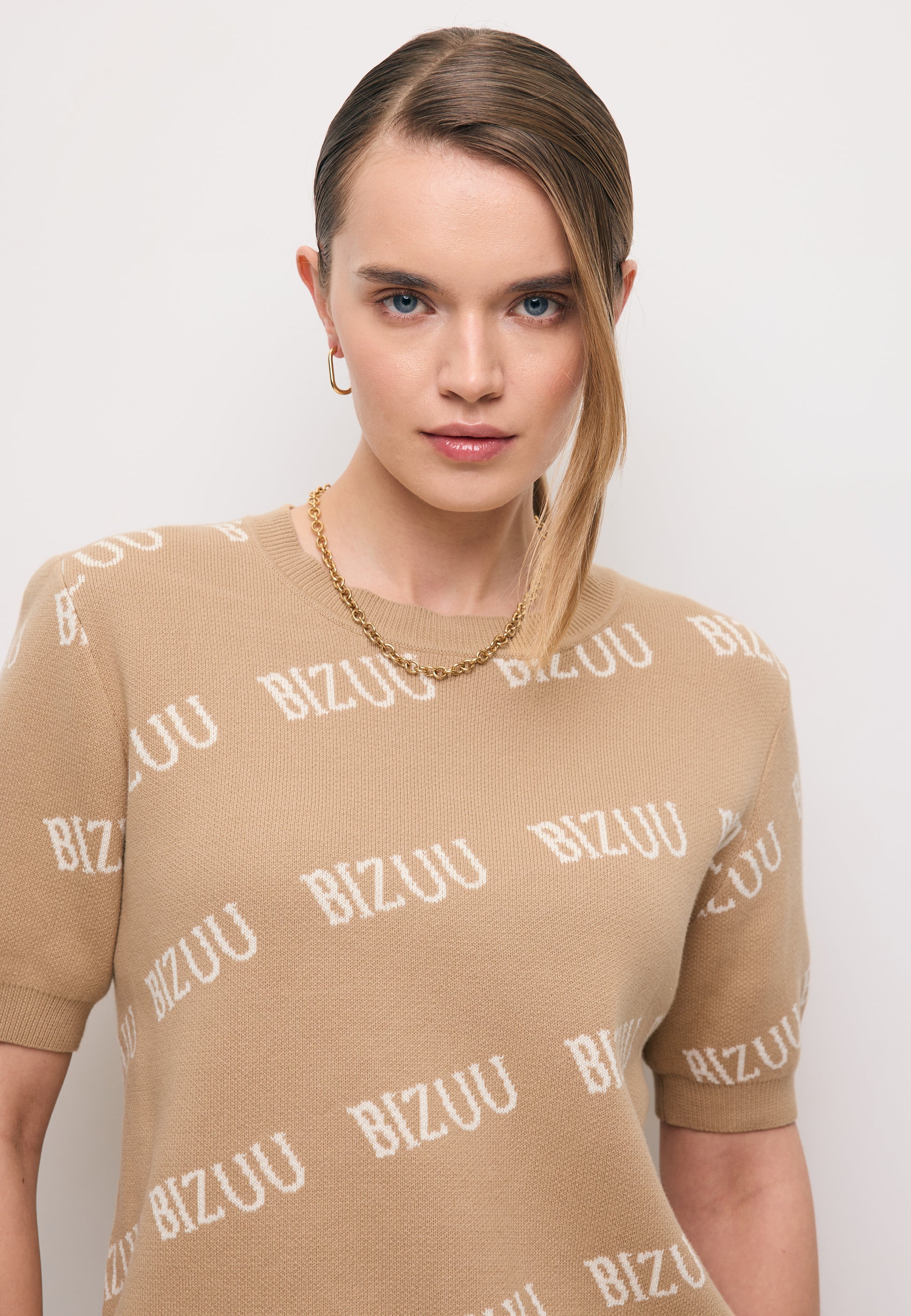 Zbliżenie na modelkę w beżowym sweterku z krótkim rękawem AYLE.