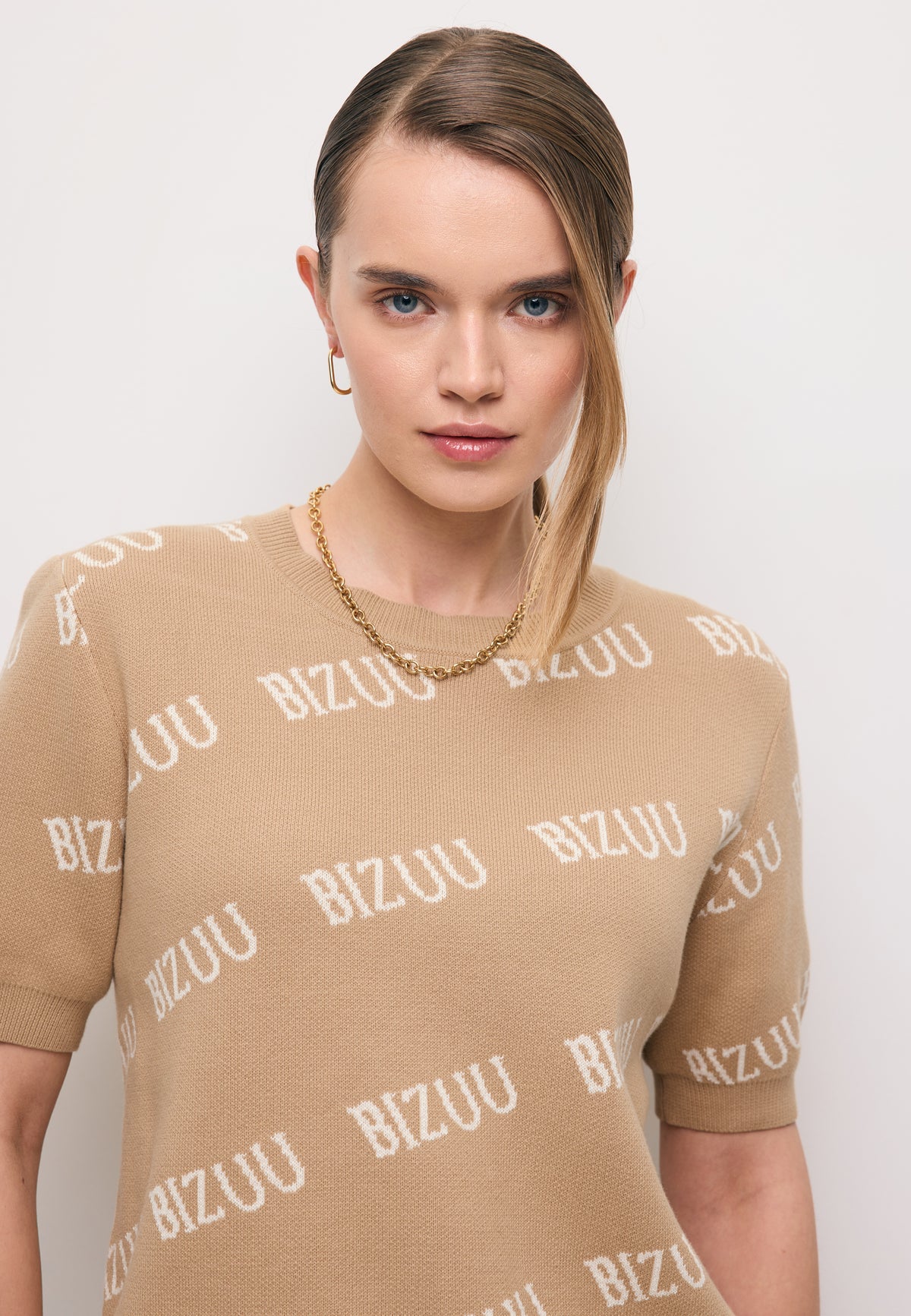 Zbliżenie na modelkę w beżowym sweterku z krótkim rękawem AYLE.