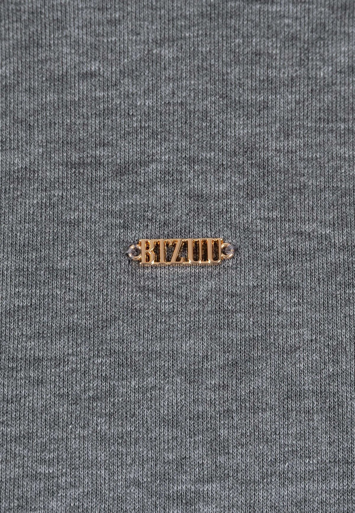 Zbliżenie na złote logo na przodzie dzianinowej sukienki CAGLIARI.