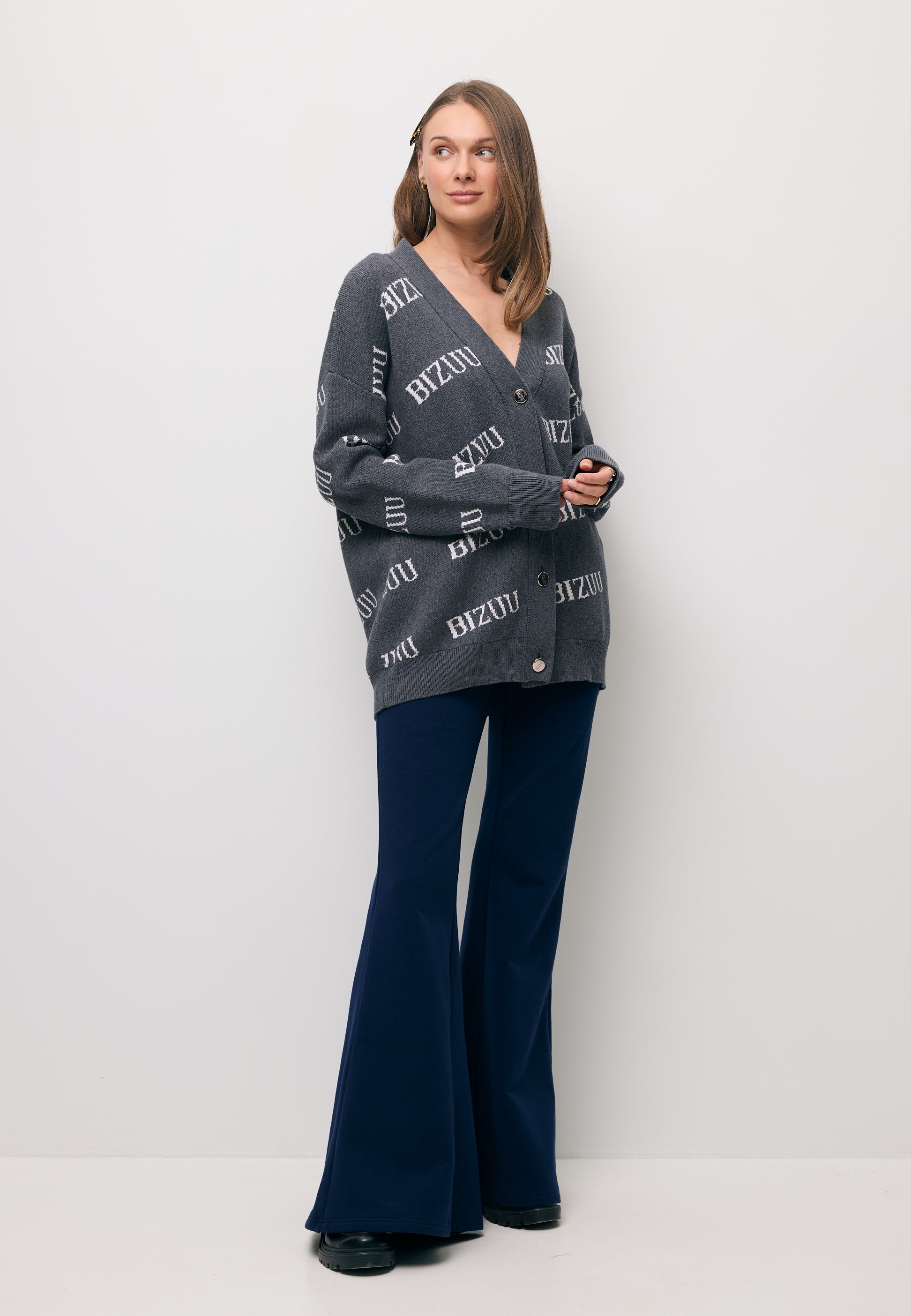 Modelka ubrana w szary, logowany kardigan KYLE oraz granatowe spodnie dresowe TEIA.