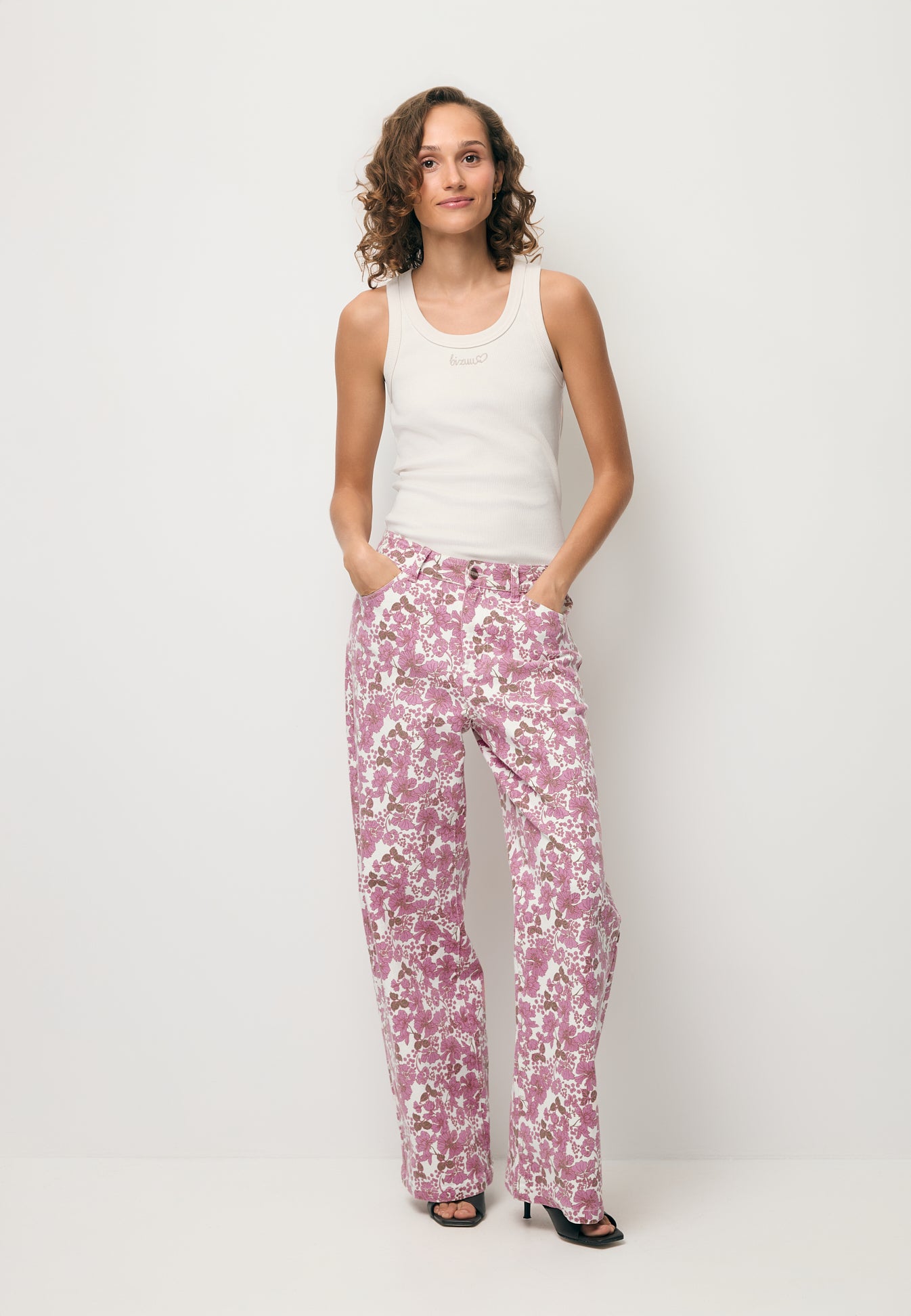 Modelka ubrana w printowane jeansy DONY oraz kremowy top z logo SEYA.
