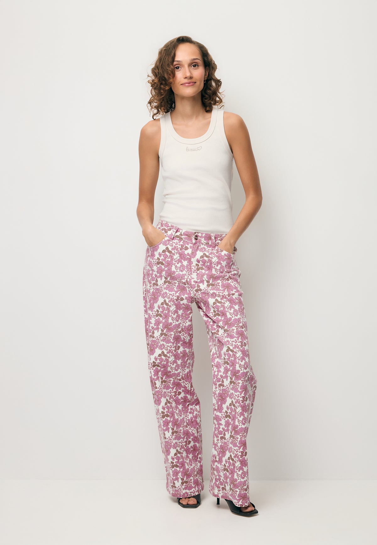 Modelka ubrana w printowane jeansy DONY oraz kremowy top z logo SEYA.