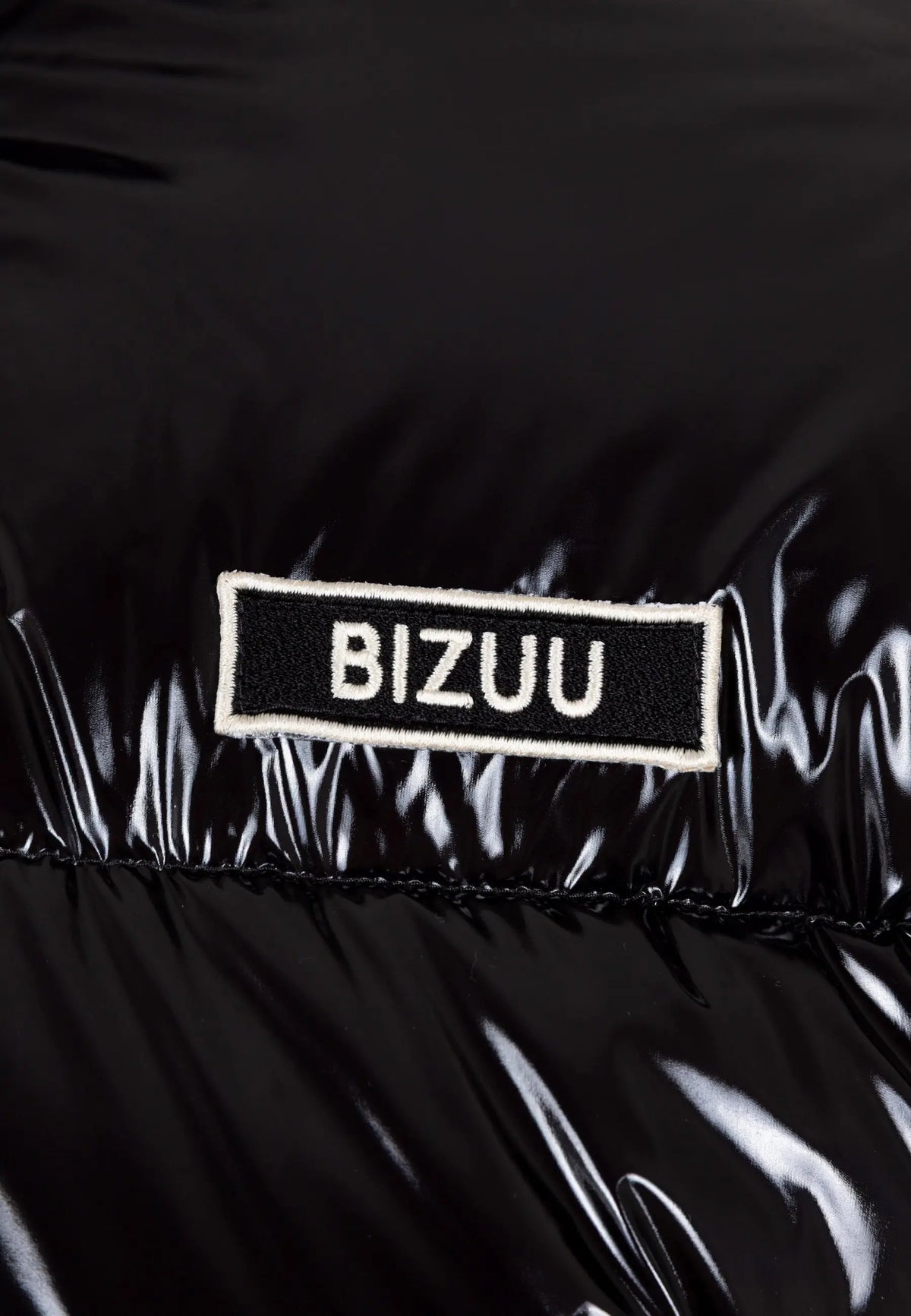 Zbliżenie na logo na przodzie kurtki puchowej SANYA.