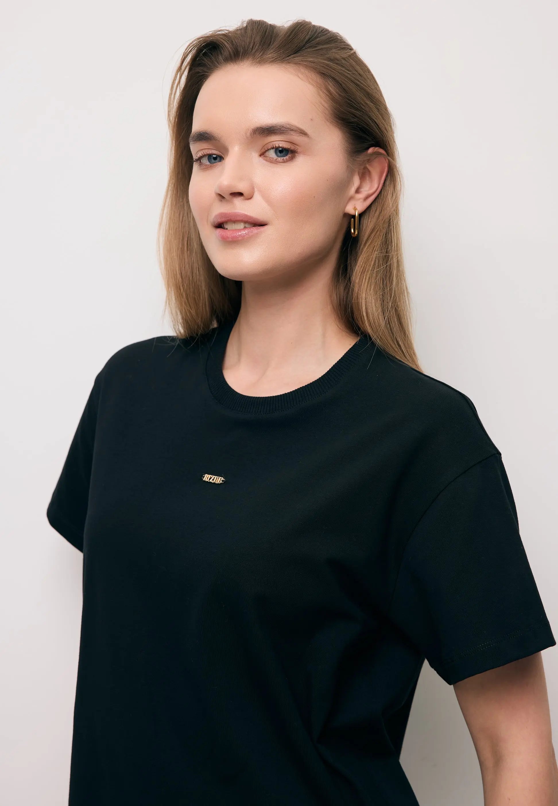 Zbliżenie na modelkę w czarnym T-shircie TISHAL z logo na przodzie.