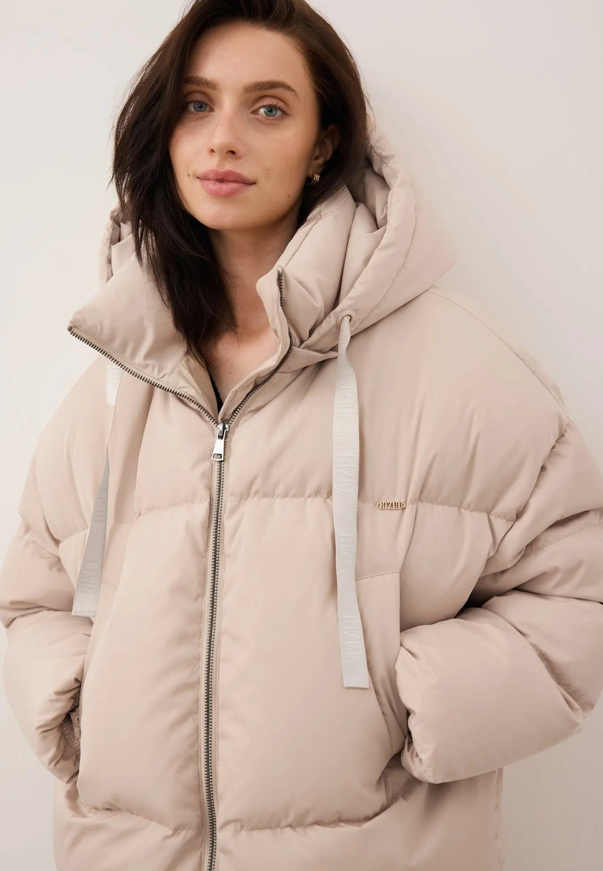 Zbliżenie na modelkę z rękoma w kieszeni zimowej, beżowej kurtki YOKO.